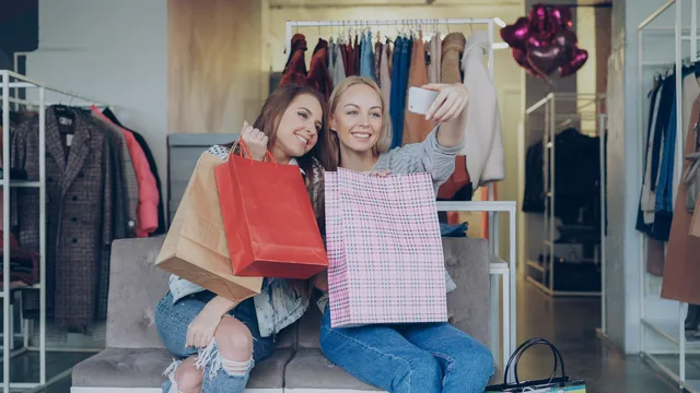 Two women with shopping bags enjoying a fun day at the clothing store and taking selfies. A social commerce outlook from merchant evidence, without inventing a 2027 market value