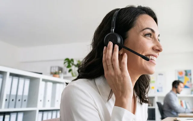 office, headset, smiling woman, headset microphone, workplace, interaction, call center, conversation, professional, communication, customer service, woman, smile, white shirt, satisfaction, working, happy worker, administrative, telephone call. Social commerce service standards defined by event, clock, owner and customer harm